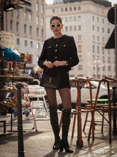 a lady wears a black tweed cropped jacket with a matching shorts
